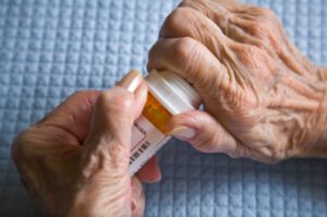 08D-5313-0 An image of the hands of an elderly person trying to unscrew a medicine bottle.