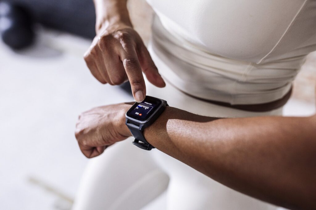 A woman checking her smartwatch for heart rate and workout stats while exercising indoors.