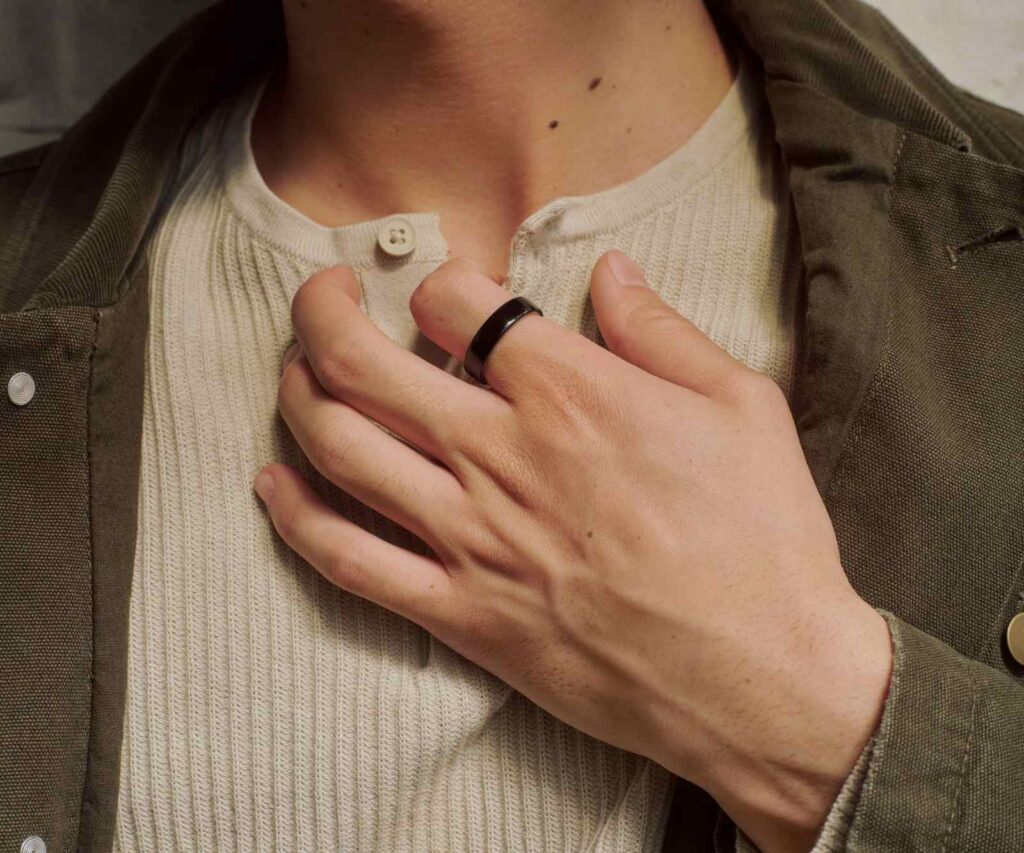 A slim smart ring in brushed silver on a neutral surface.