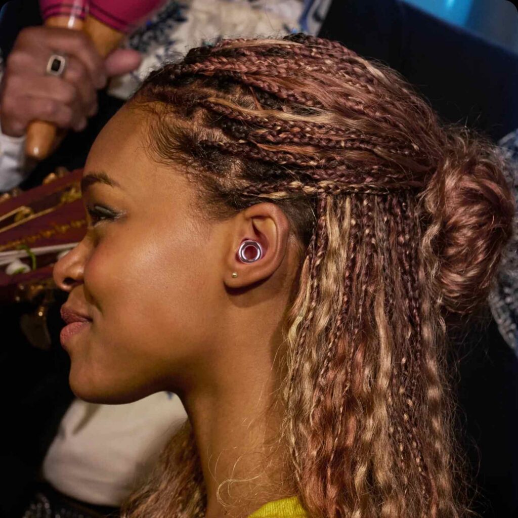A set of reusable earplugs in a woman's ear.