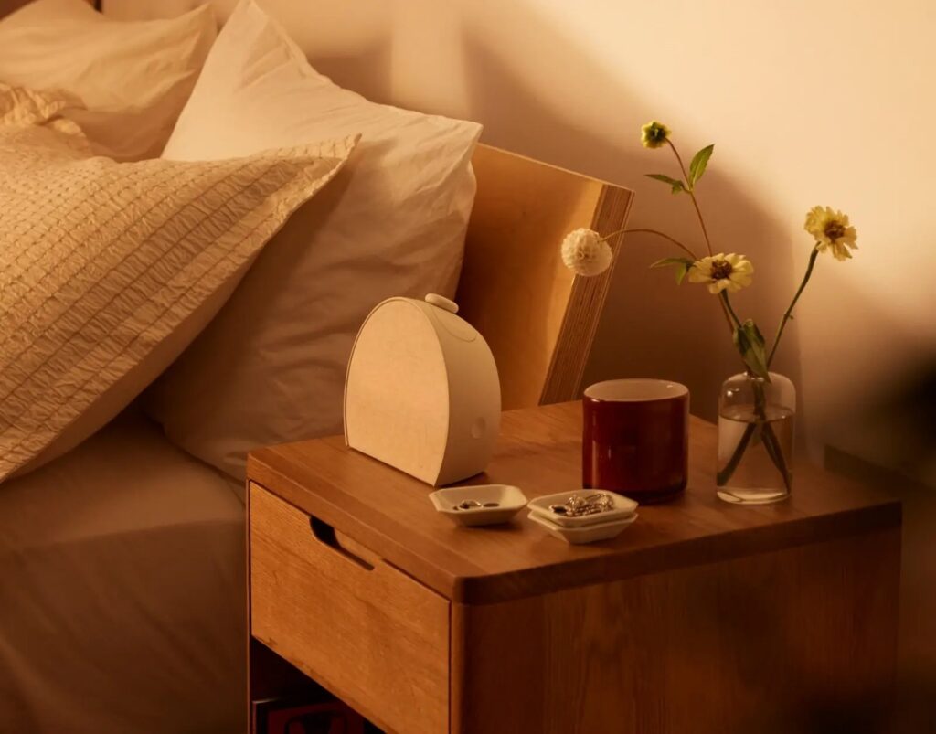 A sunrise alarm clock glowing warm orange on a nightstand.