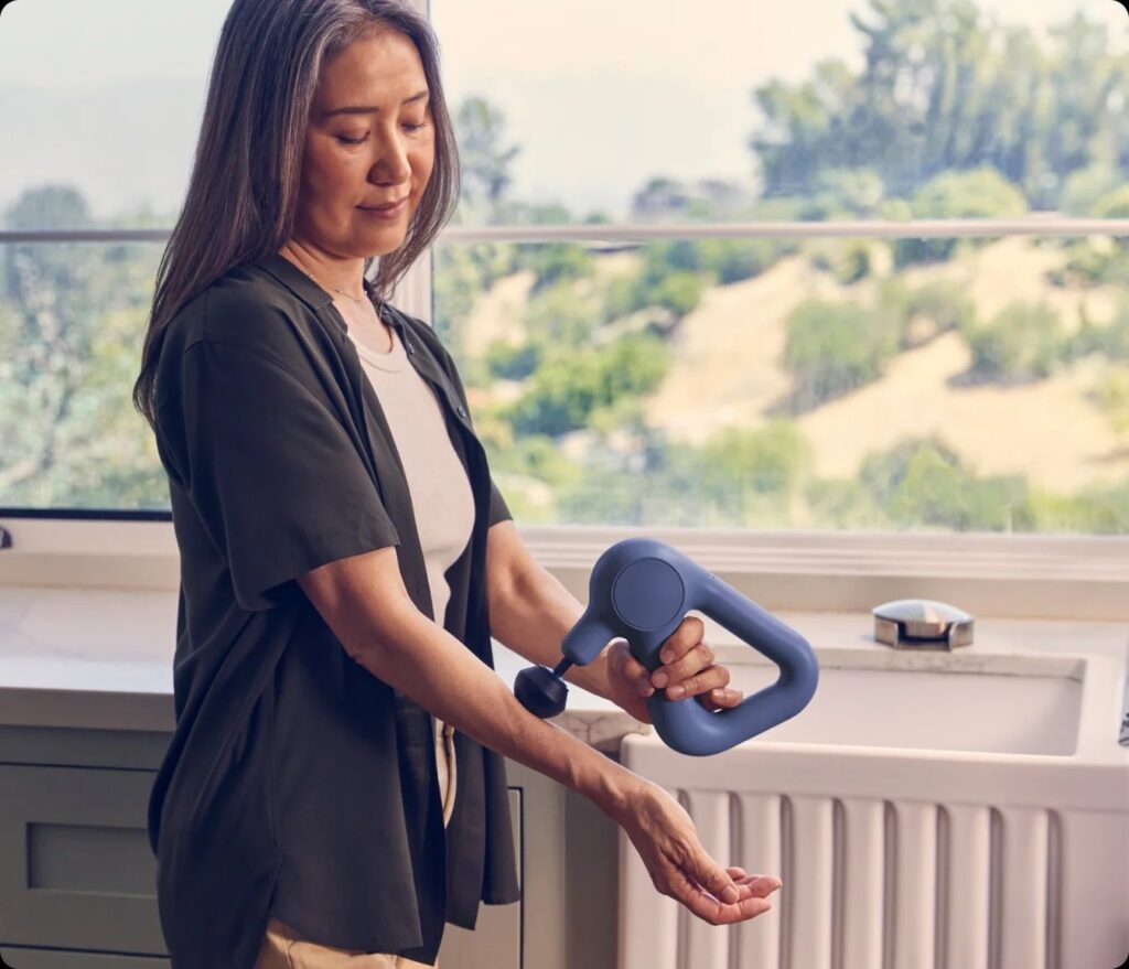 A handheld percussion massage device with a triangular grip.