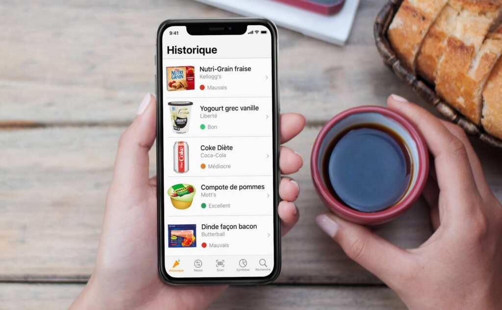 A phone showing a list of foods at a table.